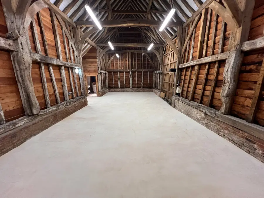 Pale microcement floor in a Grade II listed timber barn conversion, Pinner