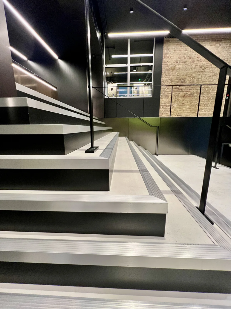 Microcement stepped seating detail with metal nosings — Lotus Cars London HQ