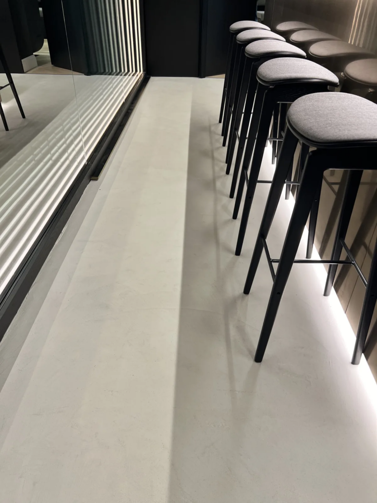 Bar seating row on microcement floor — Lotus Cars London HQ, Farringdon