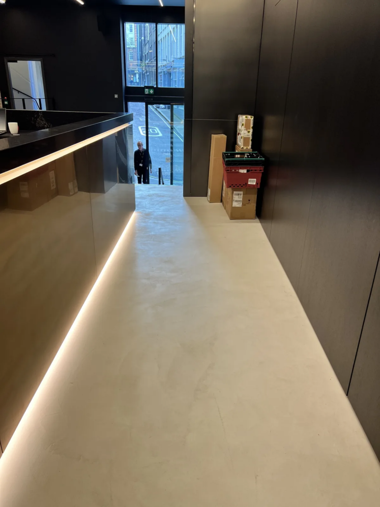 Microcement floor behind the bar, LED underlight — Lotus Cars London HQ