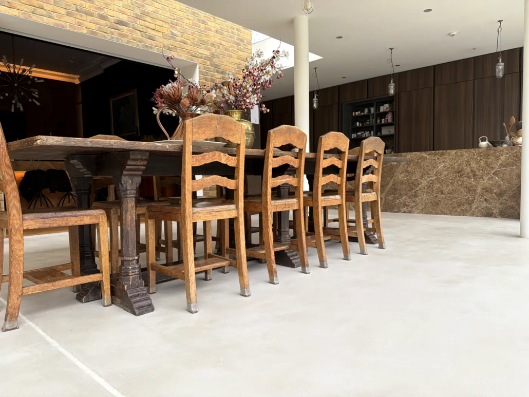Seamless microcement floor in an open-plan dining space with glass walls, Chiswick