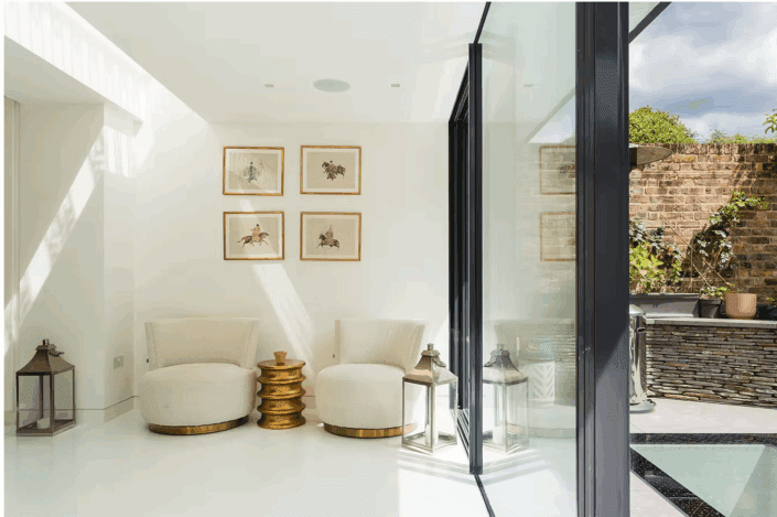 A room with white chairs, art on the wall, and polished concrete floors—modern style inspired by London interiors.